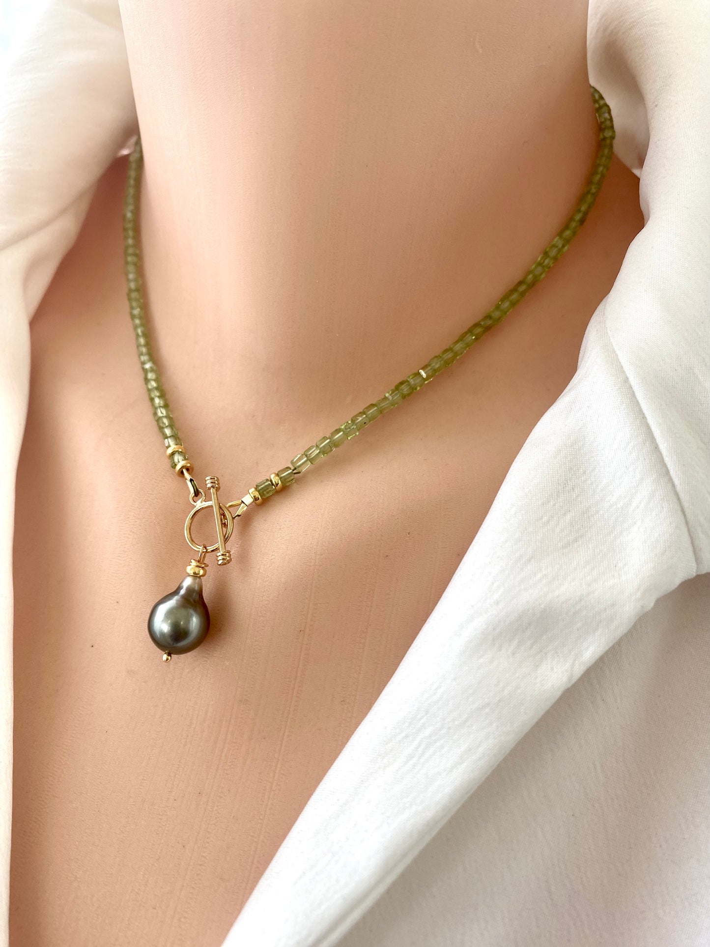 Peridot baroque pearl necklace with a toggle pendant design featuring vibrant green Peridot and a Tahitian Baroque pearl.