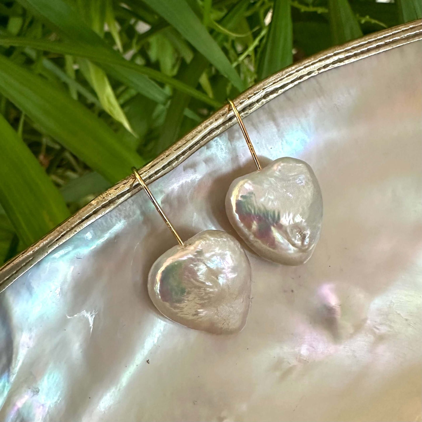 Heart shape freshwater pearl drop earrings displayed on a shell background, handmade in Canada.