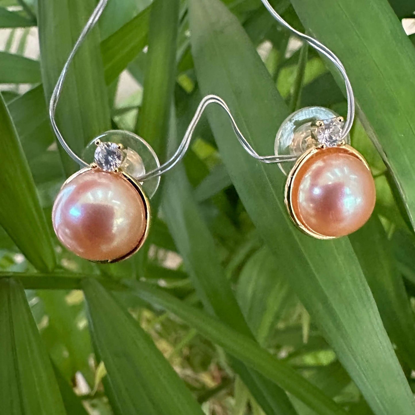 Golden peach Edison Mabe pearl stud earrings close up with green foliage background handmade in Canada