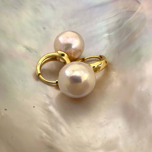 Elegant golden pink pearl hoop earrings resting on shell, highlighting iridescent luster and handcrafted gold vermeil finish.