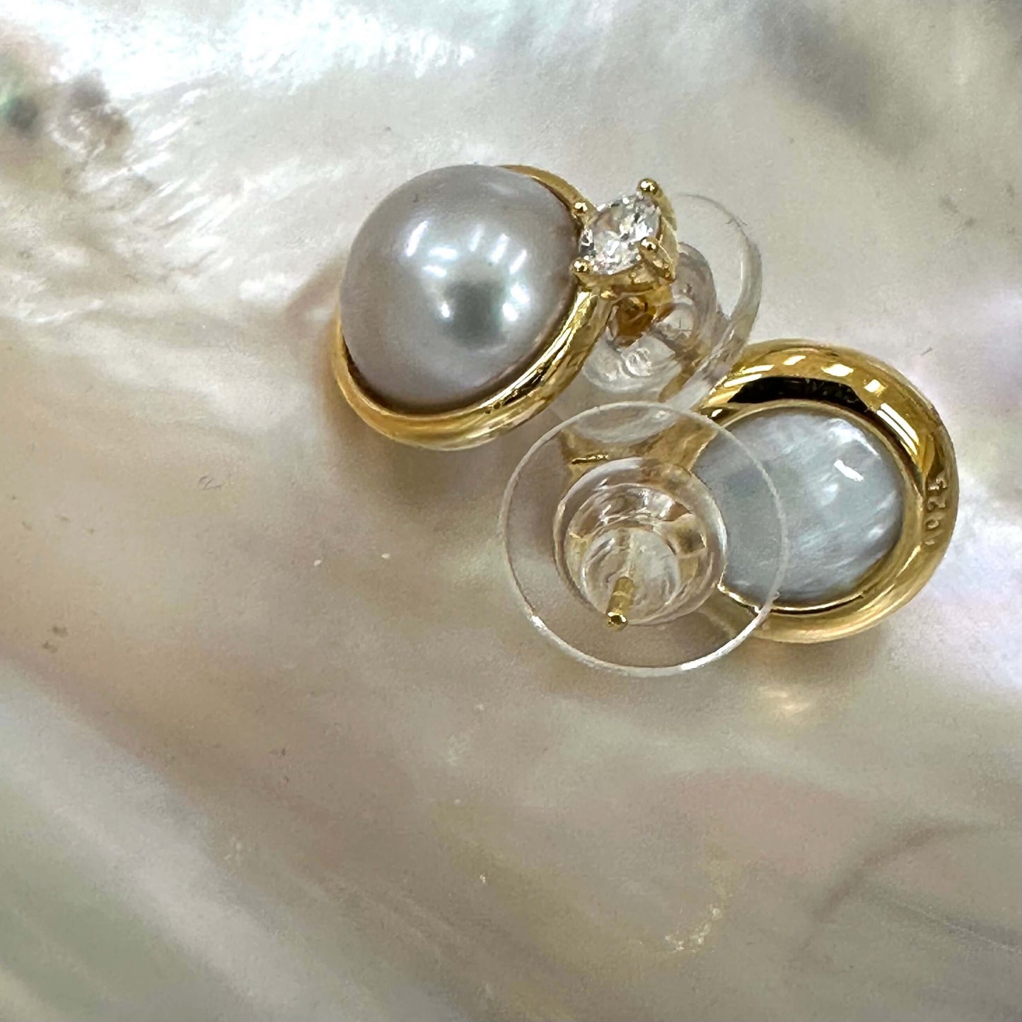 Silver grey pearl stud earrings with CZ in gold vermeil on a pearly background.