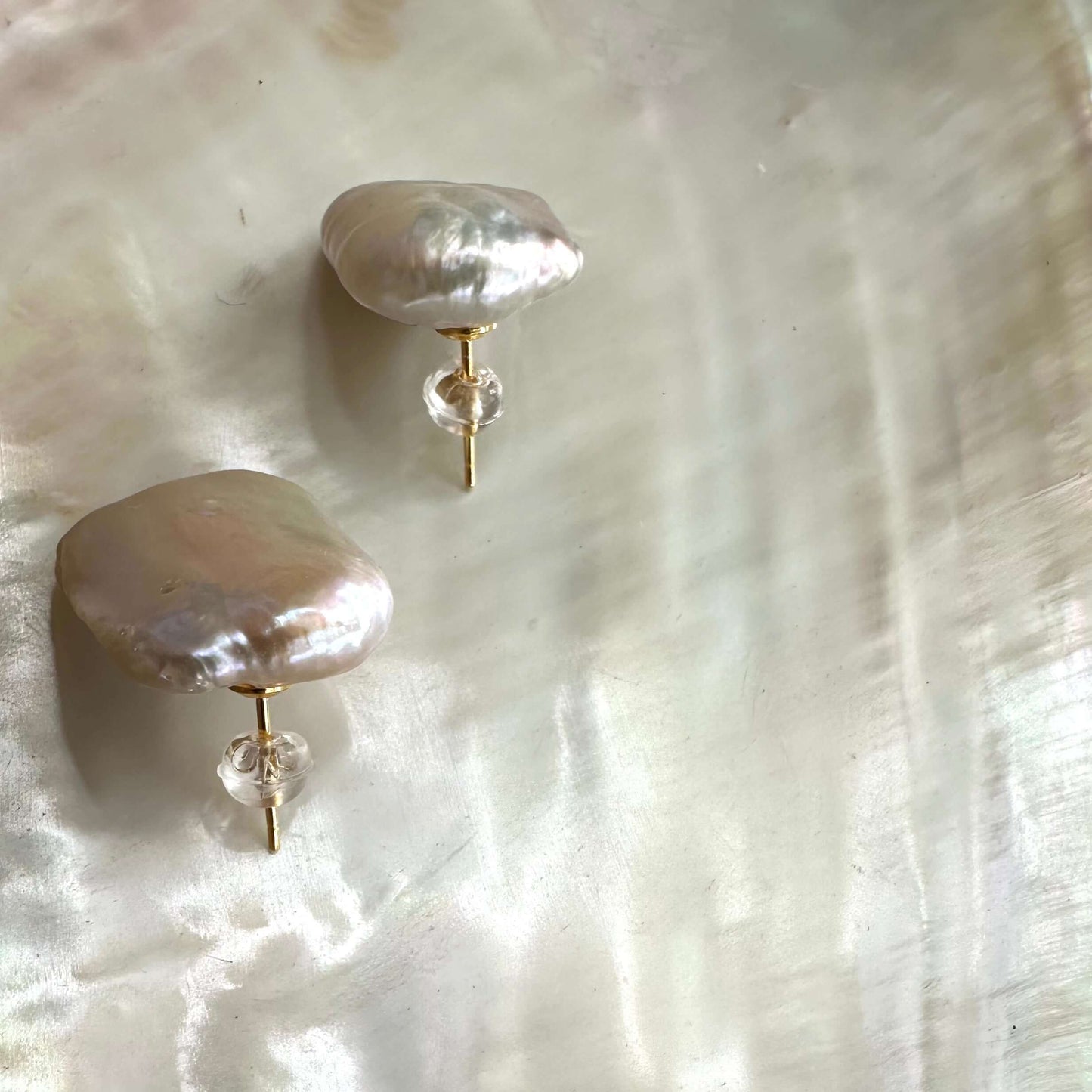 Baroque pearl stud earrings showcasing unique, organic shapes on a pearlescent background.