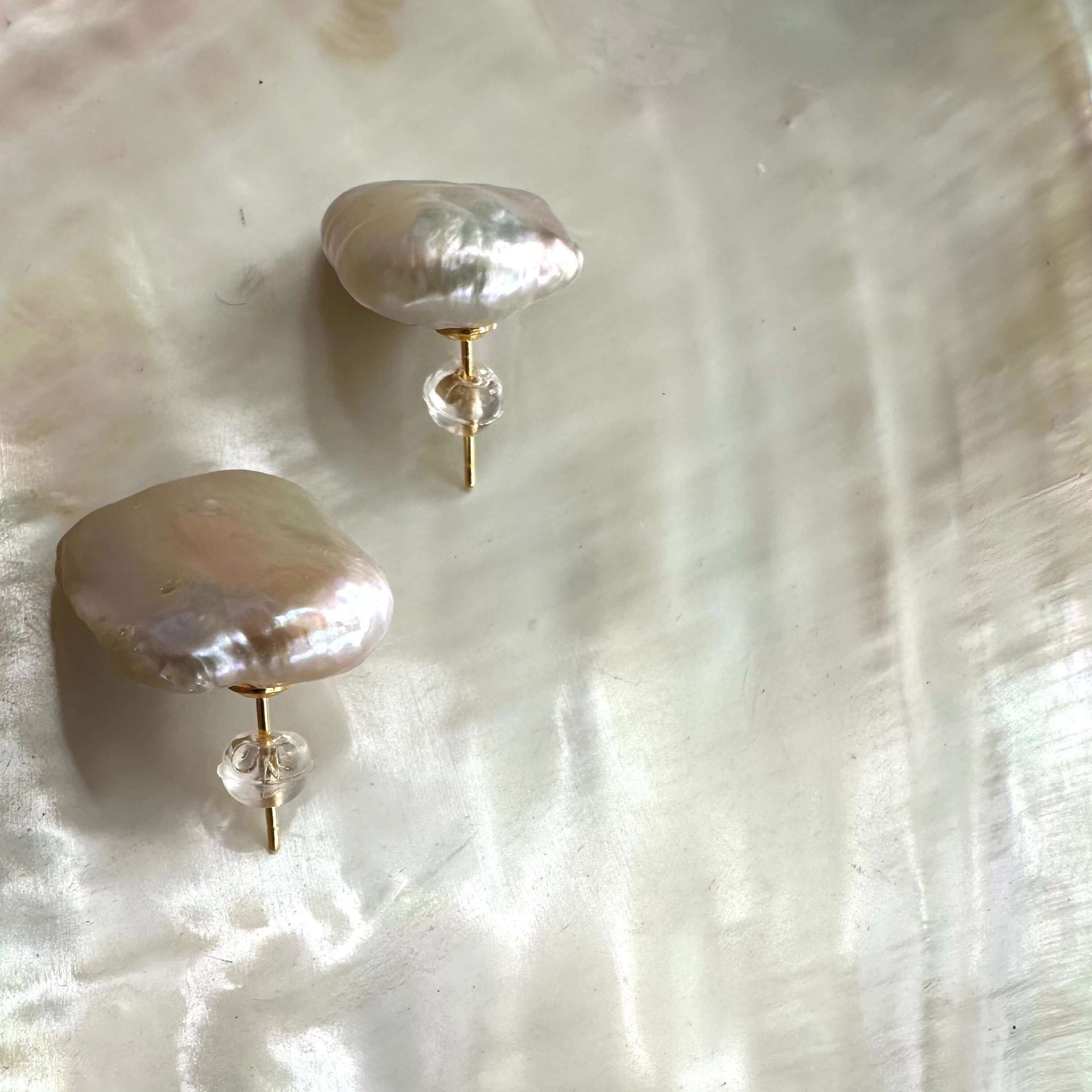 Baroque pearl stud earrings showcasing unique, organic shapes on a pearlescent background.