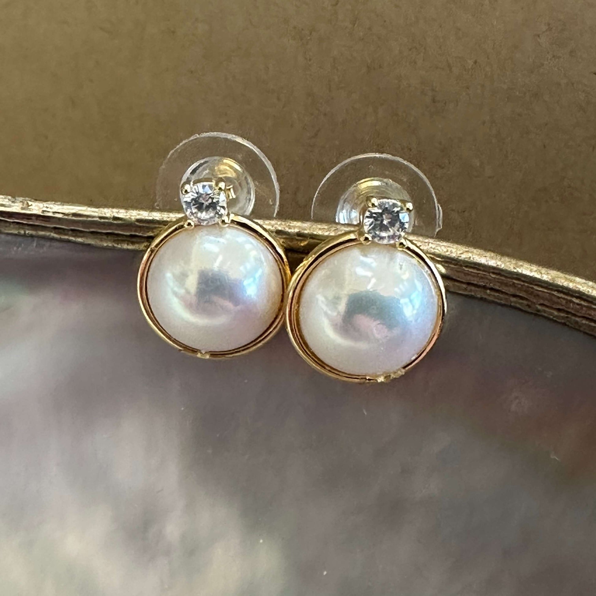 Gold vermeil Mabe Edison pearl stud earrings with CZ accents on beige background