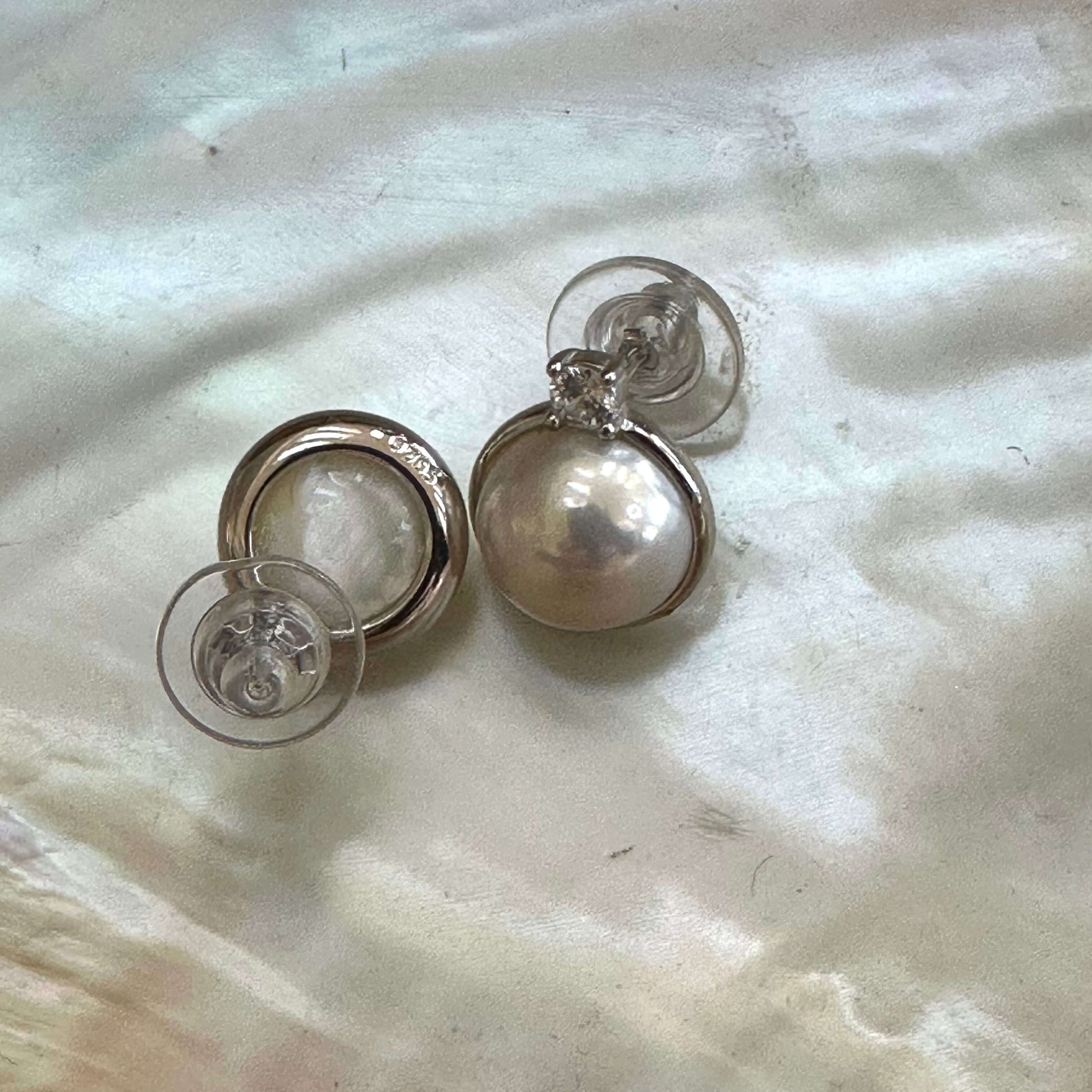 Back and front view of white mabe pearl stud earrings on white shell, highlighting sterling silver posts and handcrafted finish.