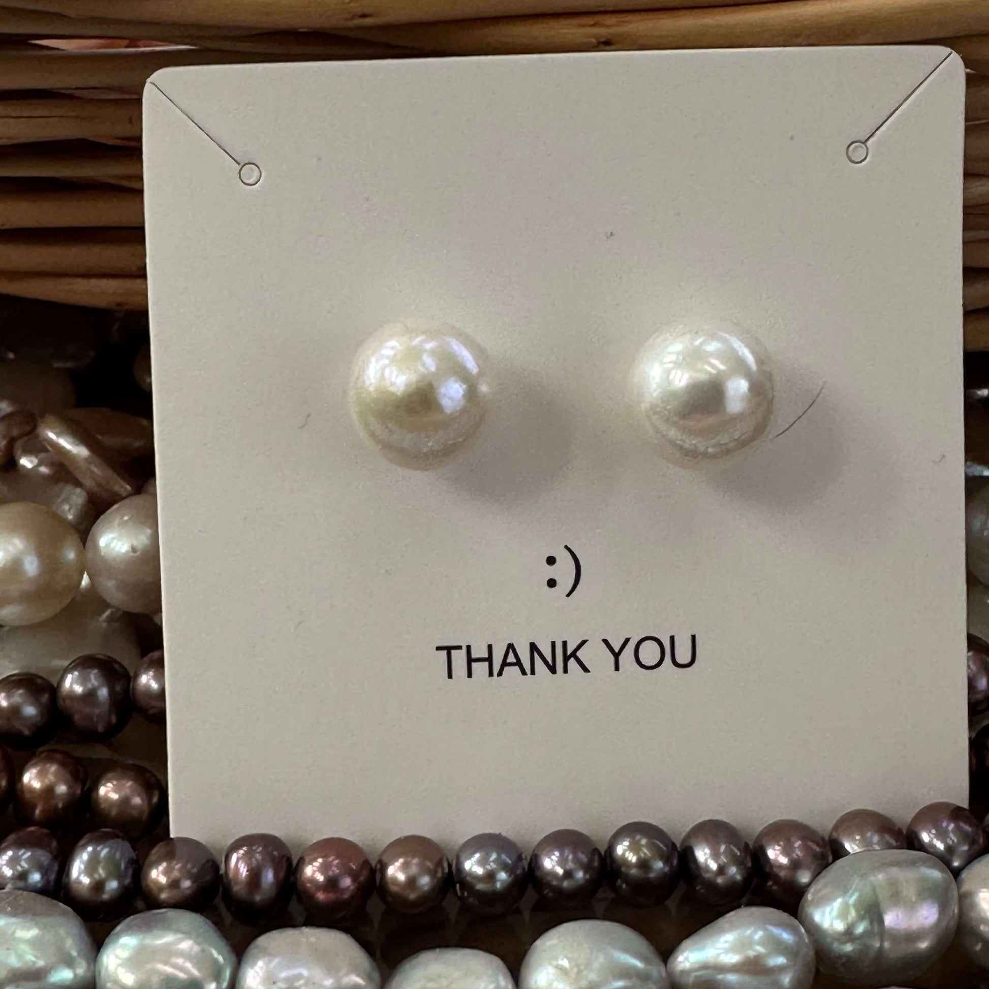 White edison pearl stud earrings attached to white jewelry package, showing gold vermeil setting and luxurious presentation.