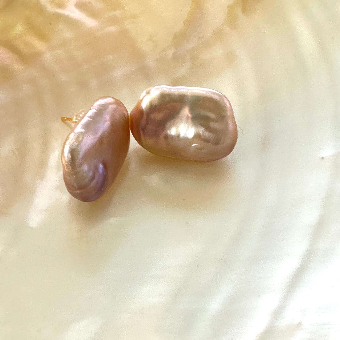 Golden pink rectangle baroque pearl stud earrings shown at side angle on luminescent yellow pearl, handcrafted in Canada.