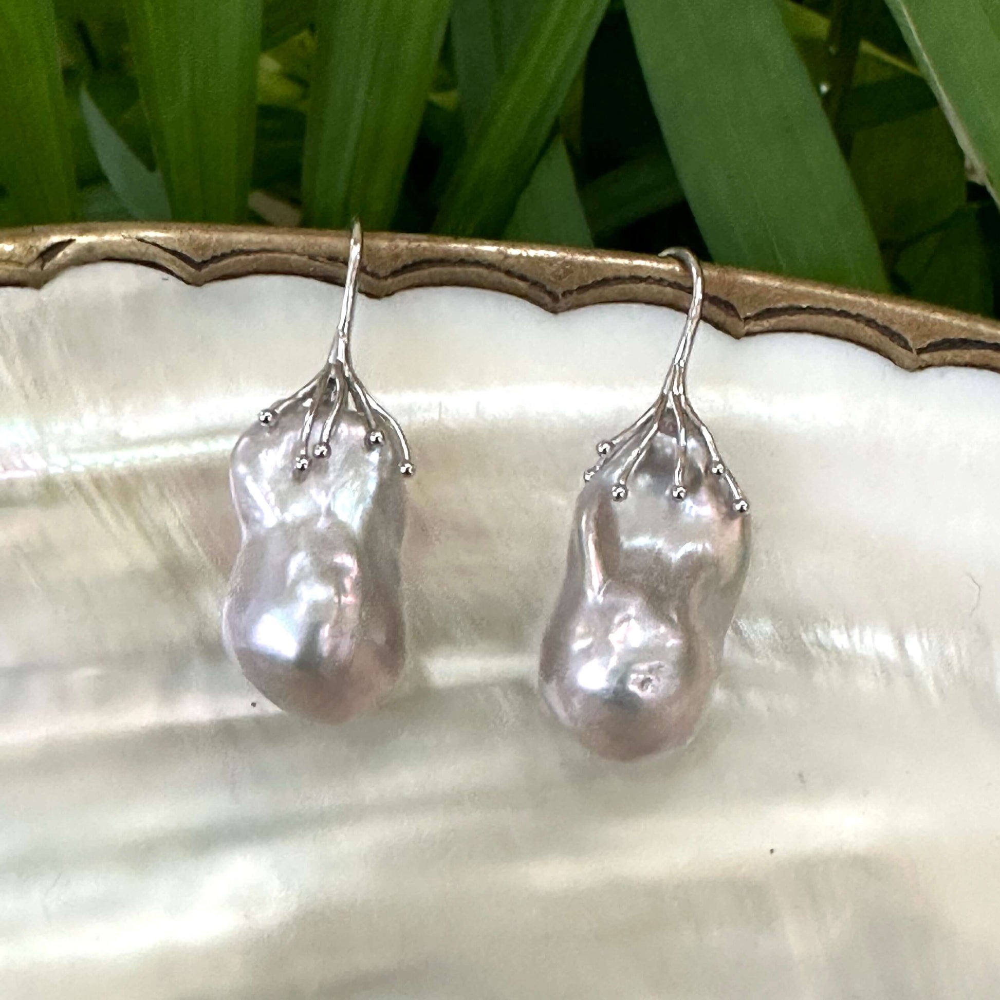 Elegant silver grey baroque pearl drop earrings photographed on white shell, highlighting organic pearl texture and shine.