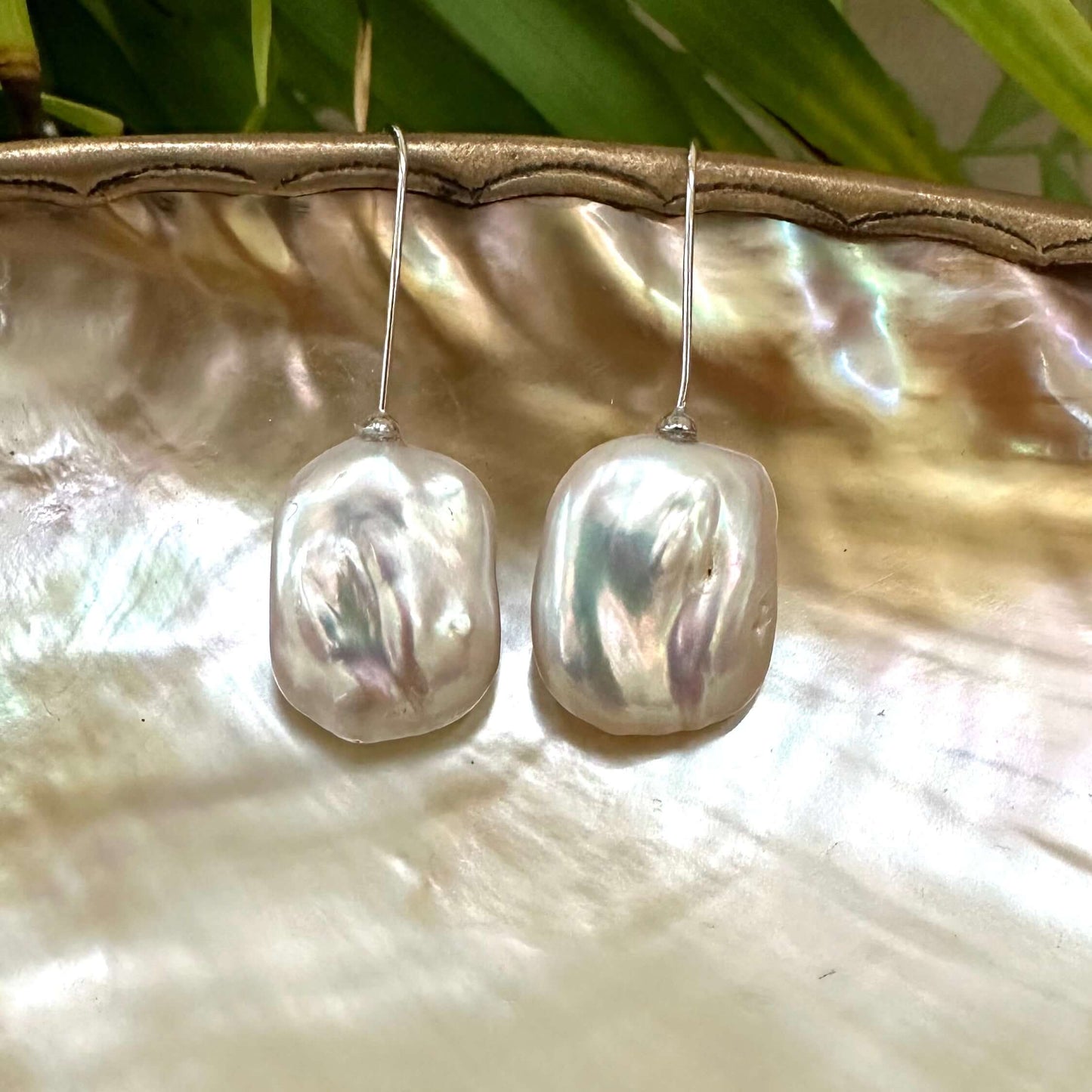 White freshwater pearl drop earrings rhodium-plated silver detailed view against leaf backdrop, elegant handmade jewelry from Canada.