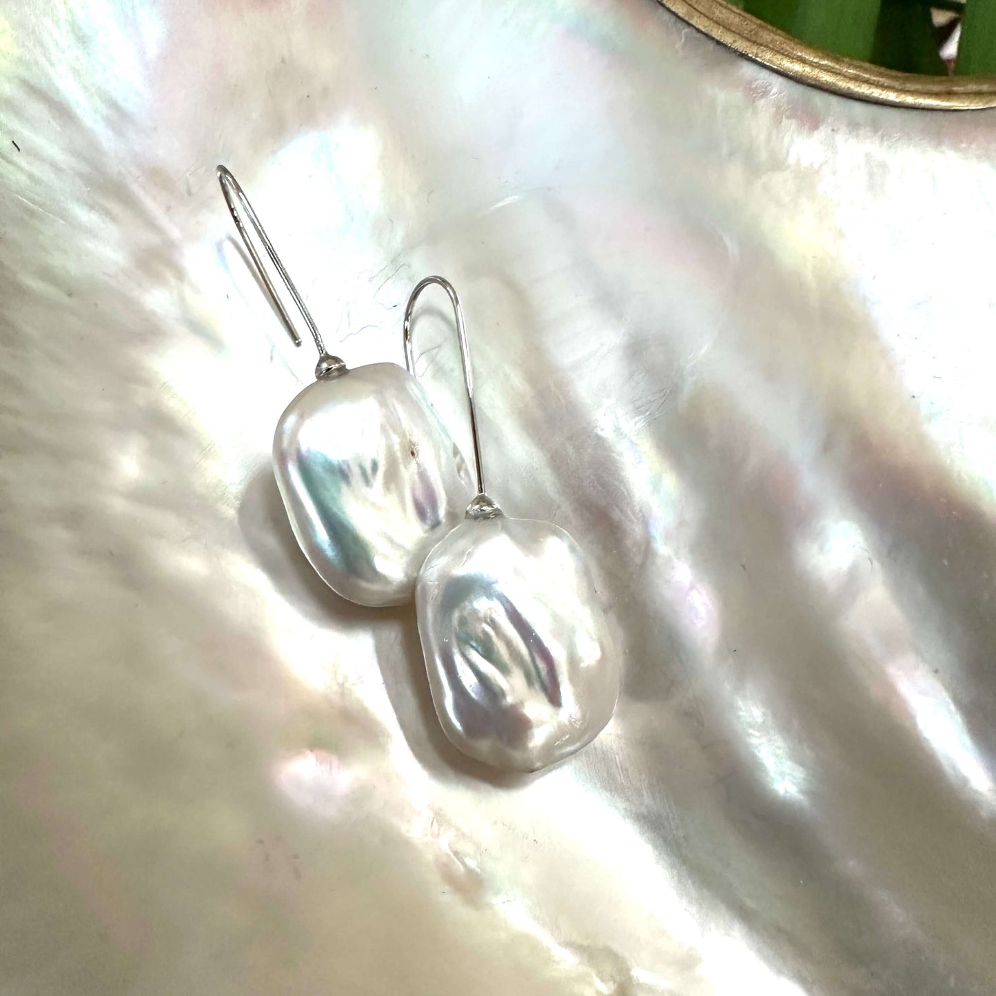 White freshwater pearl drop earrings rhodium-plated silver close-up on white pearl shell, rectangular design handmade in Canada.