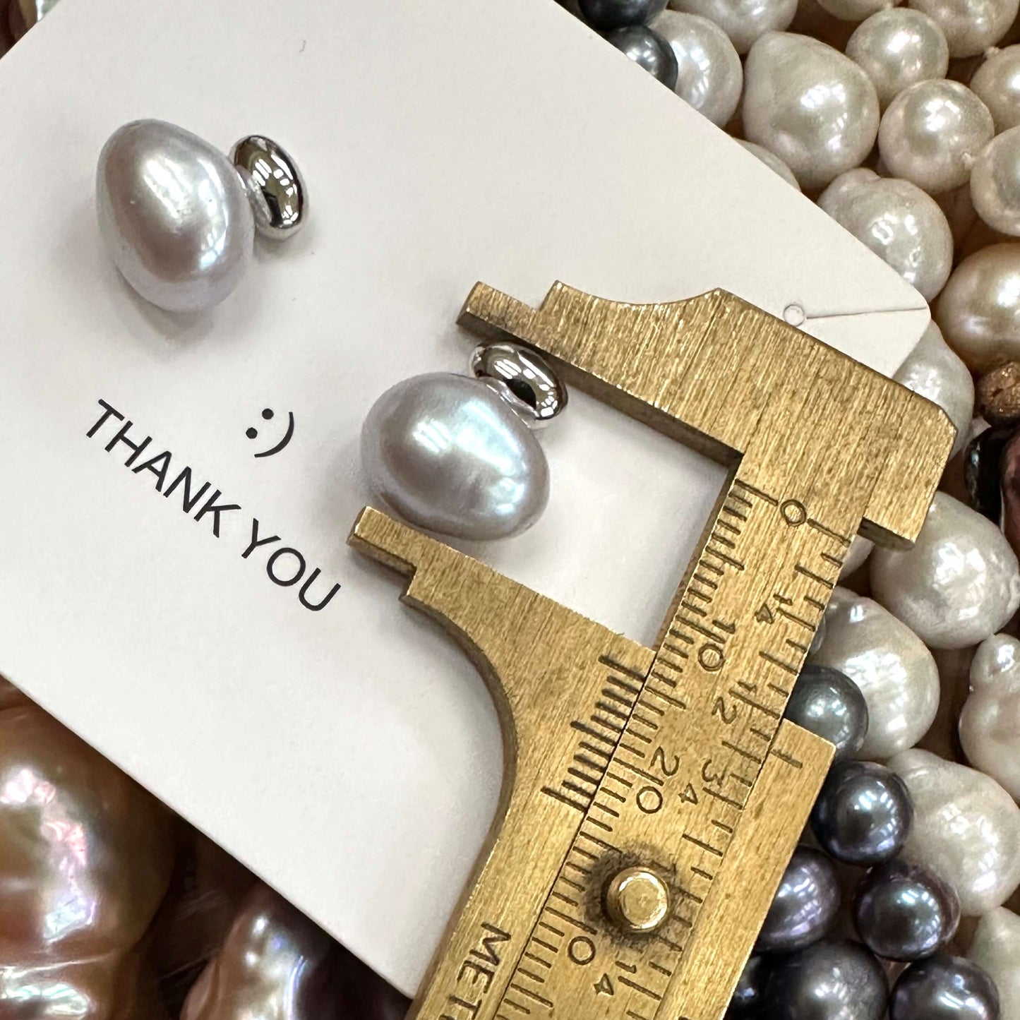 Silver grey nugget pearl stud earrings measured against ruler for size, rhodium-plated silver handmade in Canada.