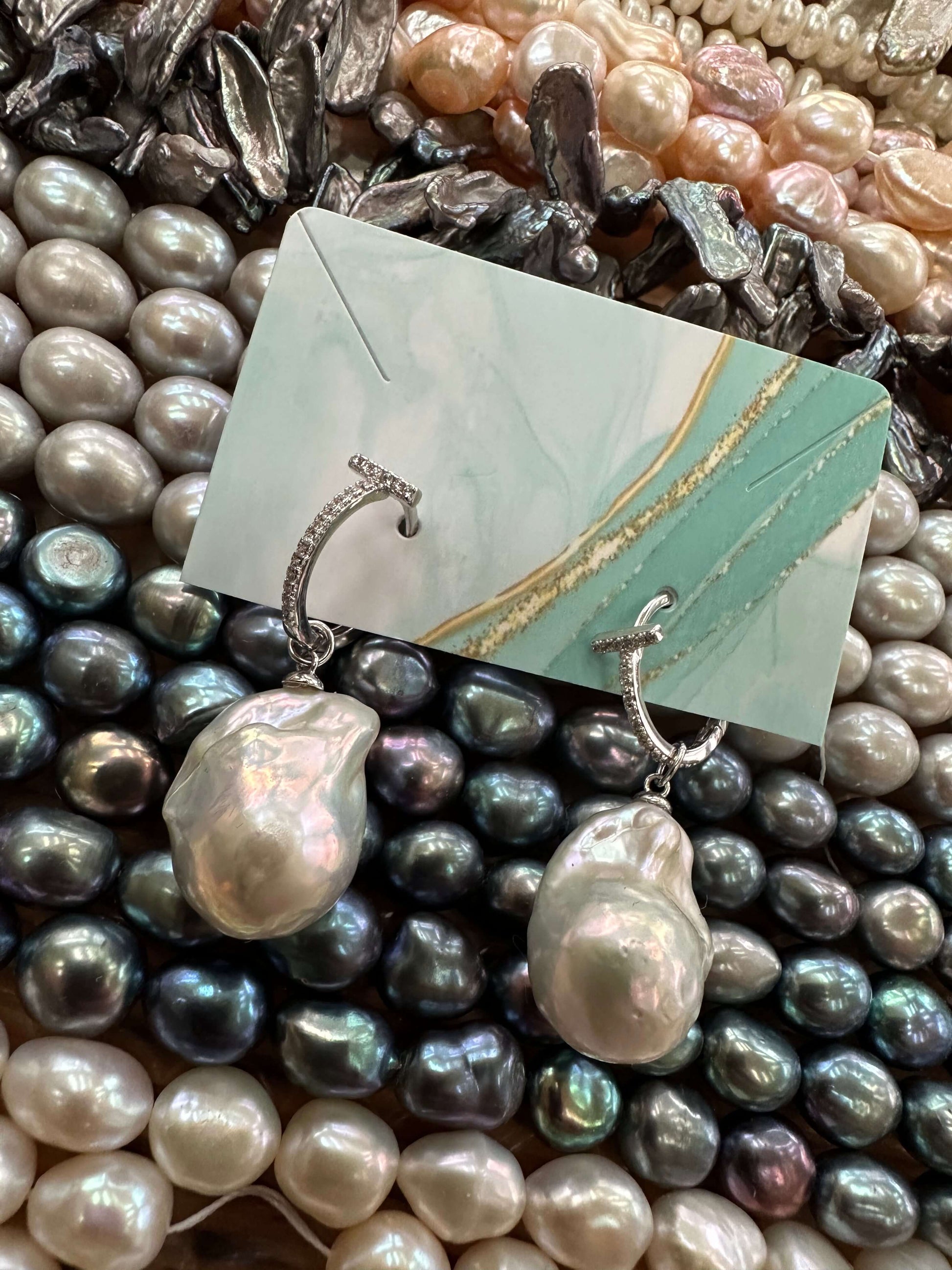 White Baroque Pearl Earrings – silver set displayed with colorful gemstones background