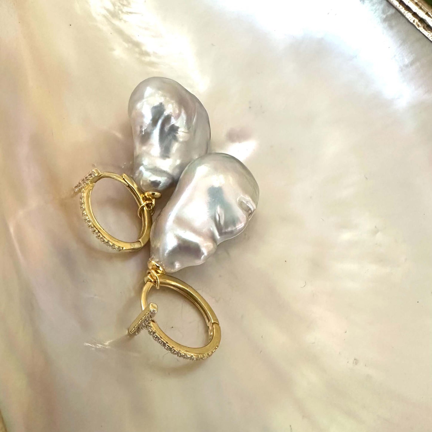 Grey baroque pearl hoop earrings displayed on white pearl shell, designed and handmade in Canada.