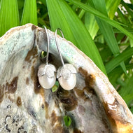 Rice Pearl Earrings – silver pair close-up on pearl shell and green foliage