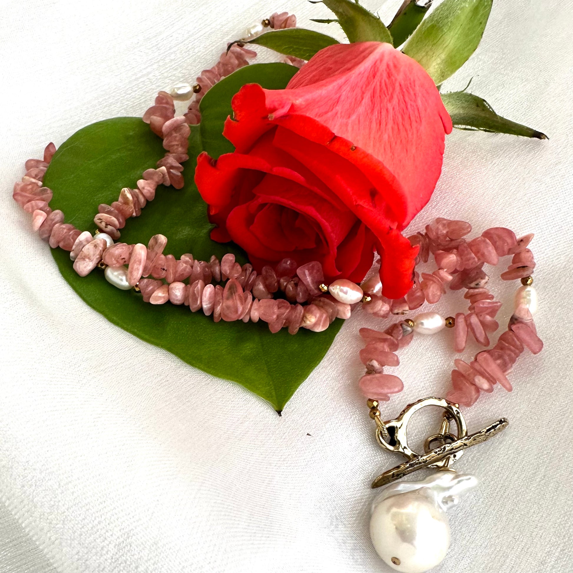 Rhodochrosite pearl toggle necklace styled with floral accent showing romantic pink gemstone tones