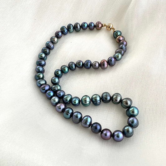 Peacock pearl necklace displayed on white cloth background