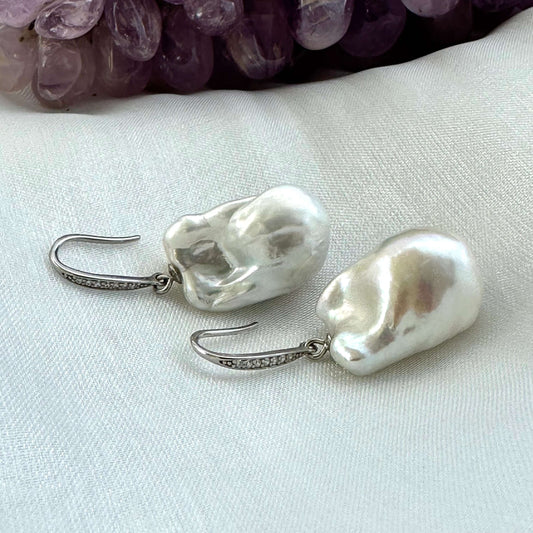 White baroque pearl bridal earrings placed on white cloth table, sterling silver CZ pavé hooks handmade in Canada.