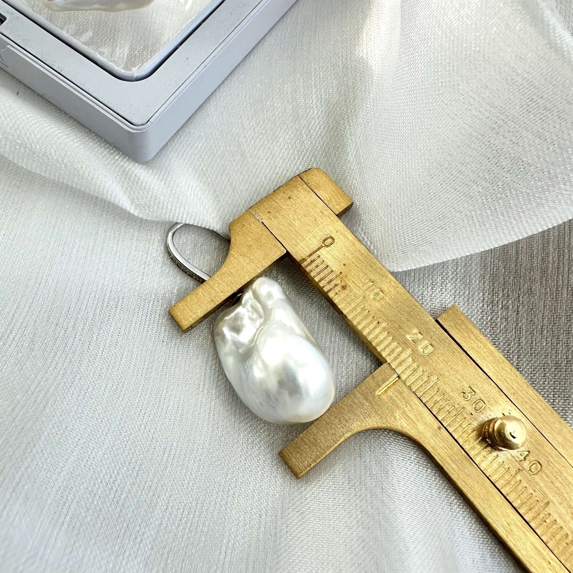 White baroque pearl bridal earrings pearl measured with ruler on white cloth, handcrafted jewelry from Canada.