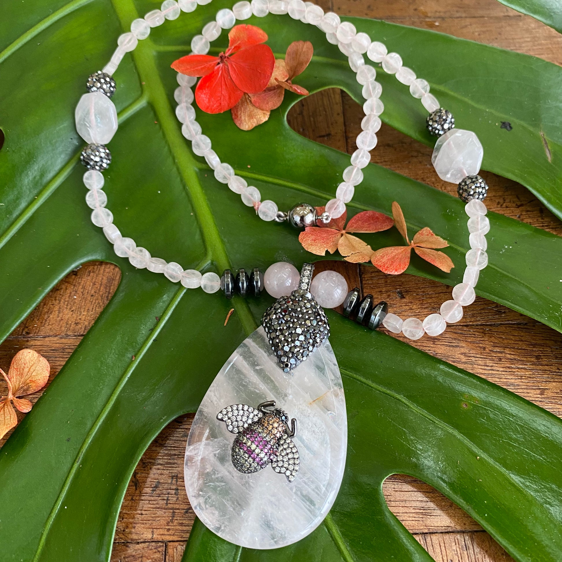 Rose quartz necklace with rhinestone pavé bee pendant, featuring soft blush-pink gemstones and playful design.
