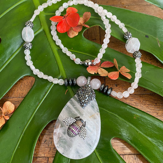 Rose quartz necklace with rhinestone pavé bee pendant, featuring soft blush-pink gemstones and playful design.