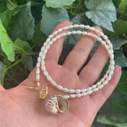 Real seashell pendant pearl necklace held in hand showing natural seashell pendant and pearl strand