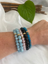 Load image into Gallery viewer, Aquamarine stretch bracelet in various colors, 6mm and 8mm beads, featuring gold filled accents on a wrist.
