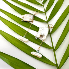 Charger l&#39;image dans la galerie, Boho pearl earrings gold filled held against leafy green background — handcrafted square pearl earrings with blue accent by Loulia Pearl Jewelry
