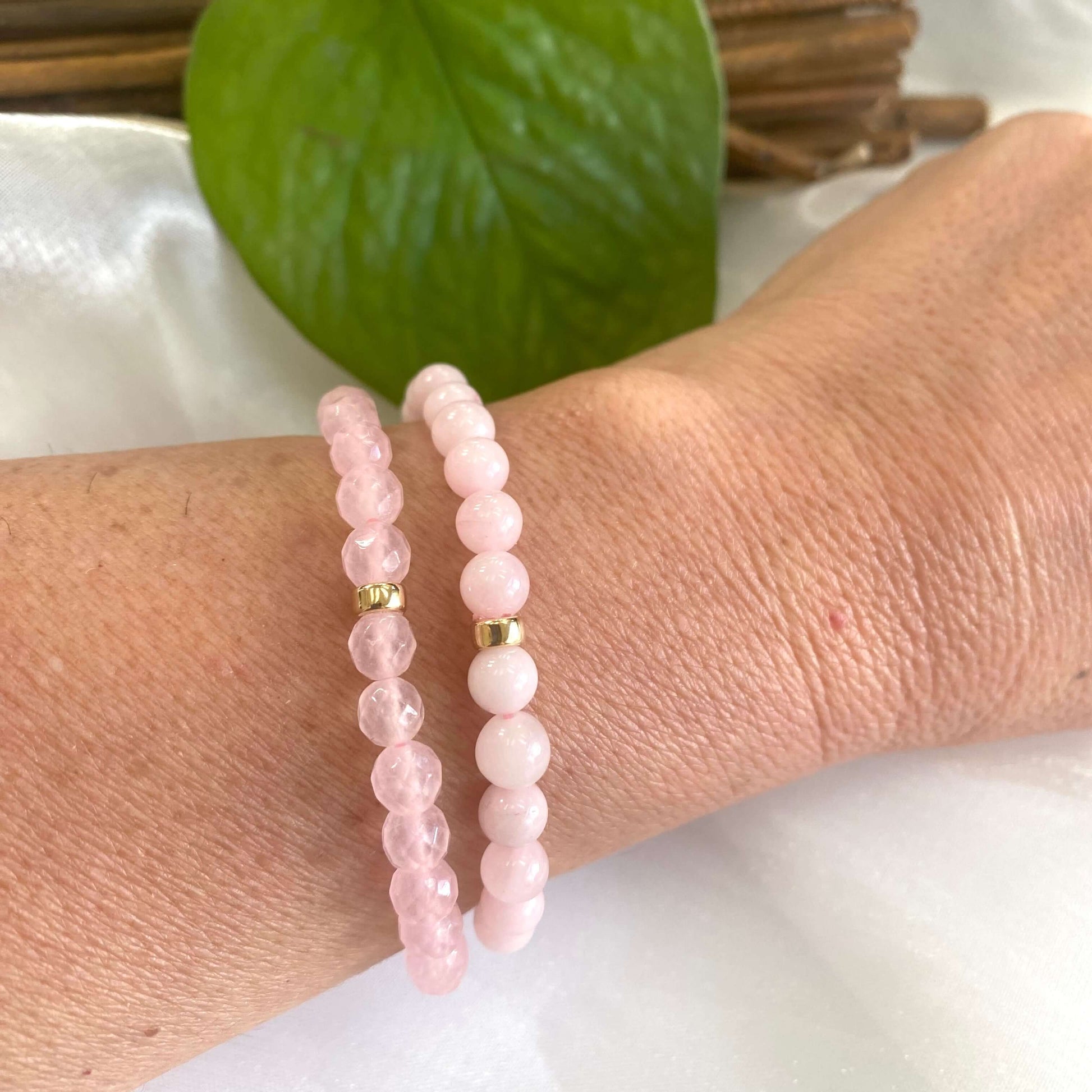 Rose quartz stretch bracelet with 6mm beads on a wrist, showcasing its soft pink hues and gold accents.