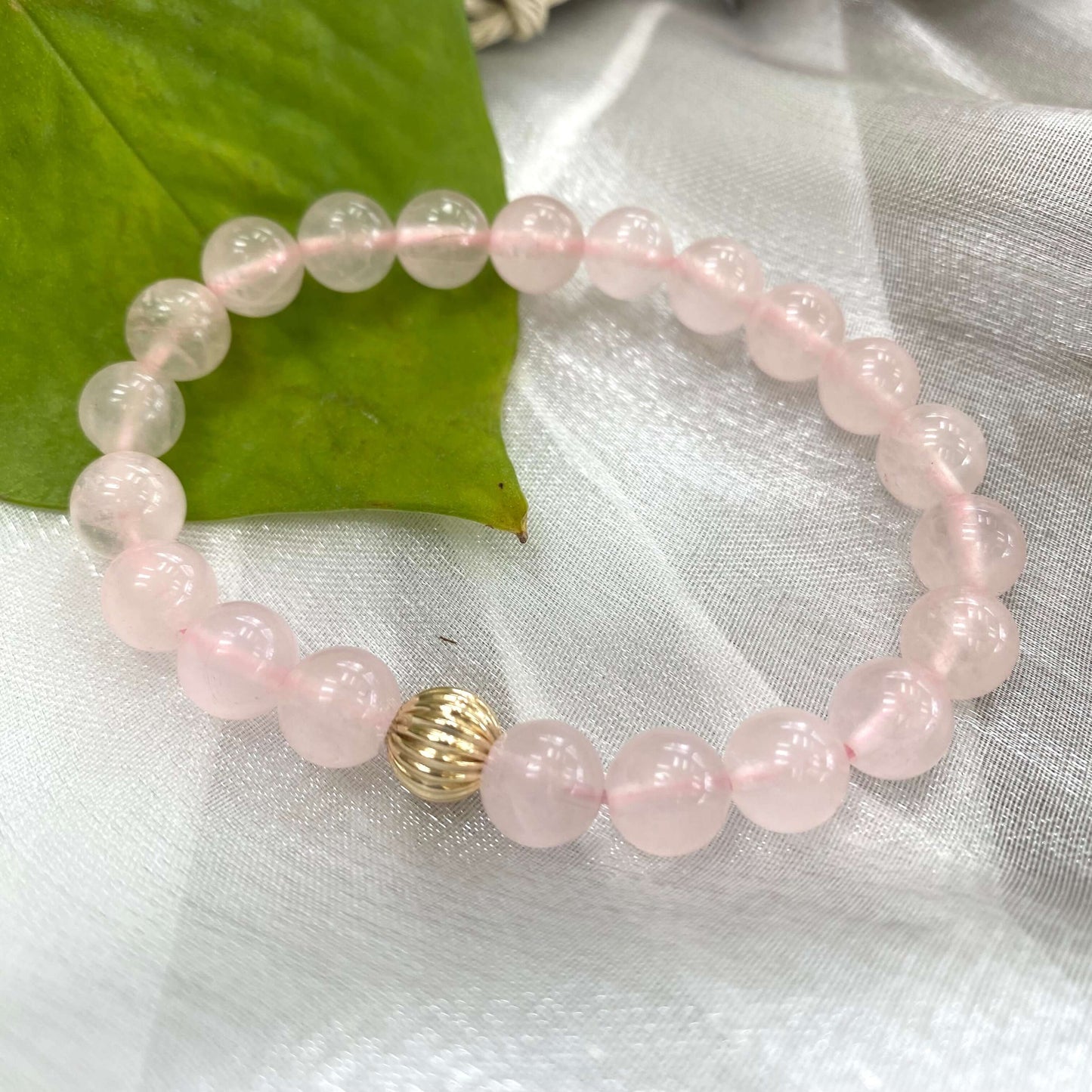 Rose Quartz Bracelet close-up on white cloth – pink gemstone bead texture
