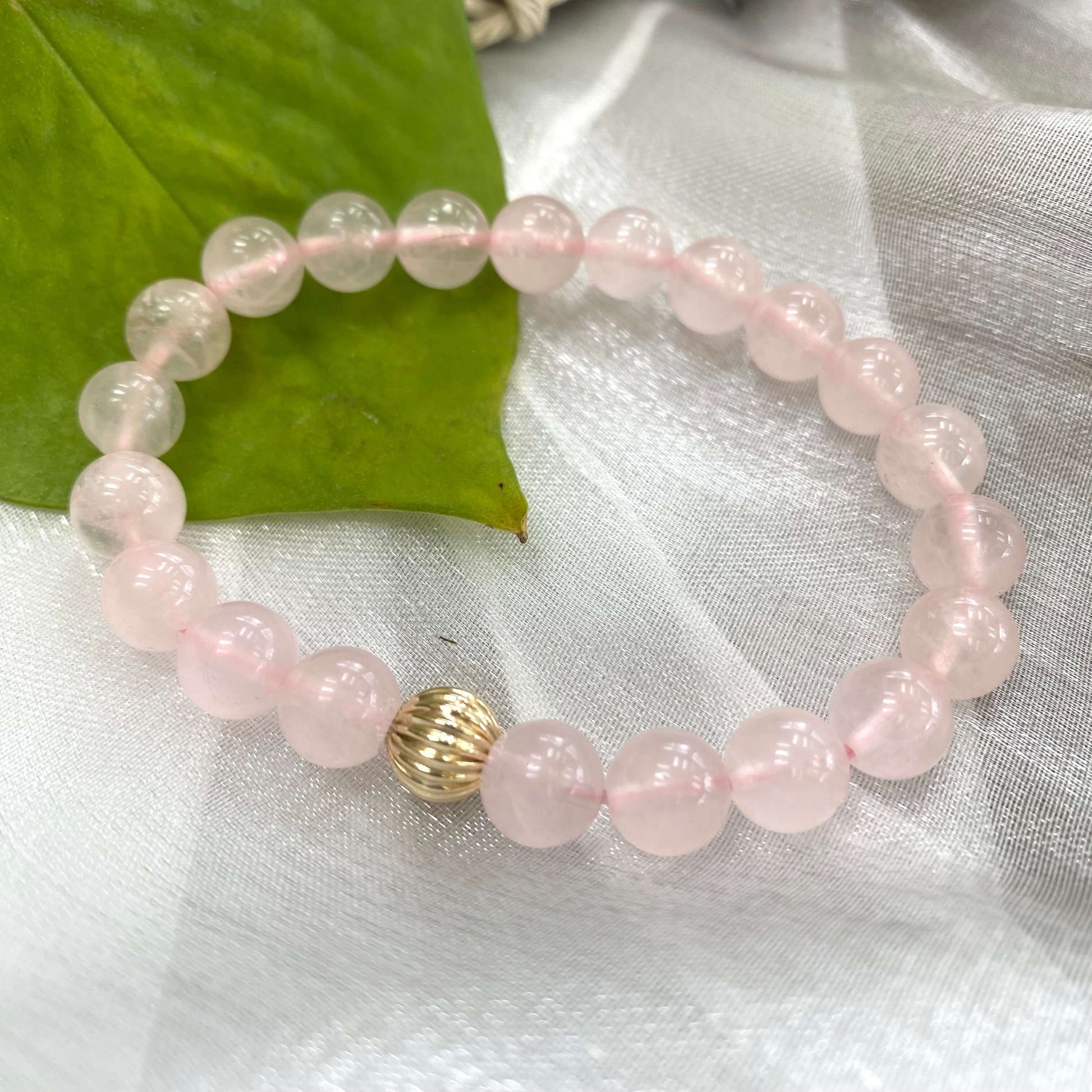 Rose Quartz Bracelet close-up on white cloth – pink gemstone bead texture