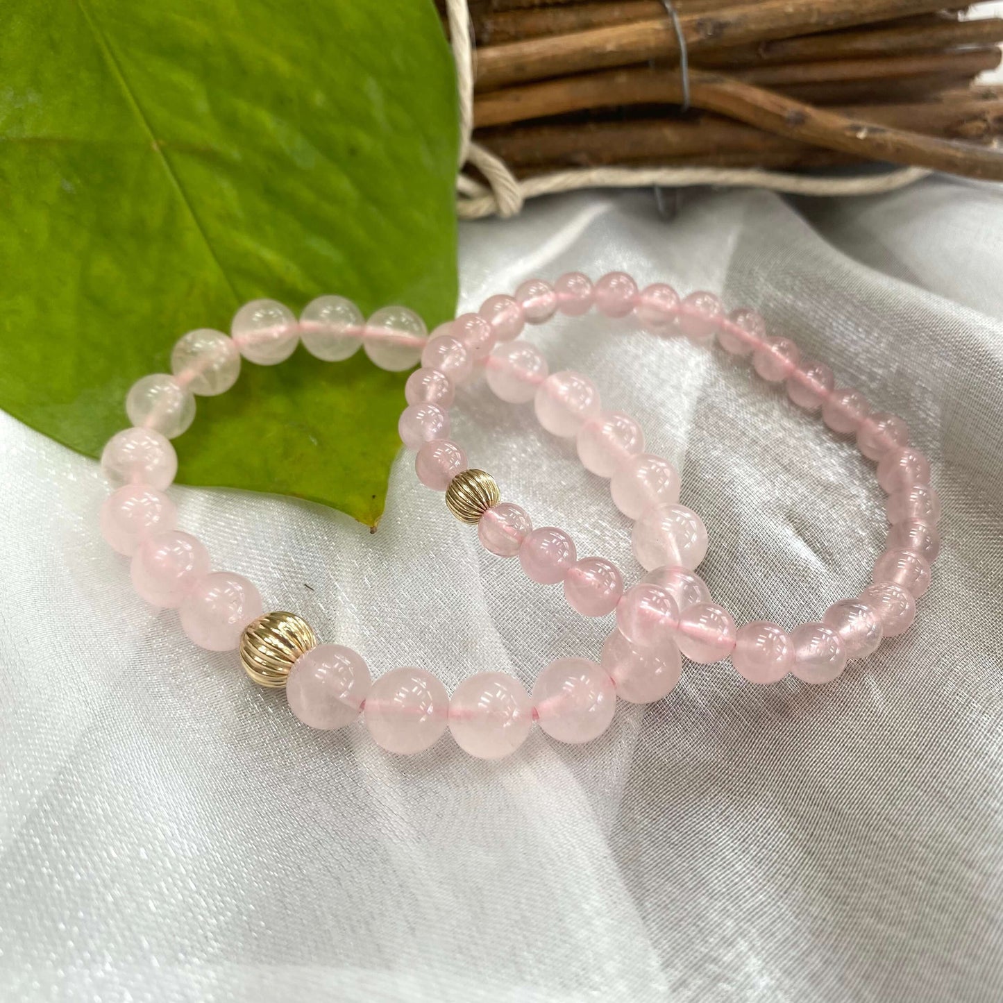 Rose Quartz Bracelet duo on white cloth – 6mm and 8mm bead comparison