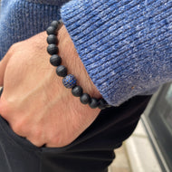 Matte black onyx mens bracelet with blue CZ, worn on wrist, showcasing stylish stretch design.