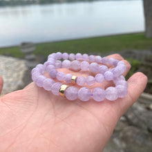 Load image into Gallery viewer, Lavender Amethyst Bracelet held in hand against lake view – outdoor close-up
