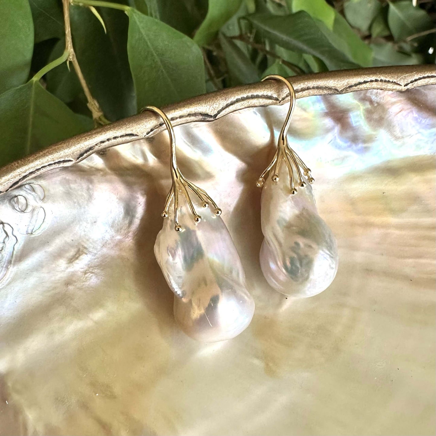 Close-up of freshwater baroque pearl earrings showing iridescent pink green hues on pearl shell surface