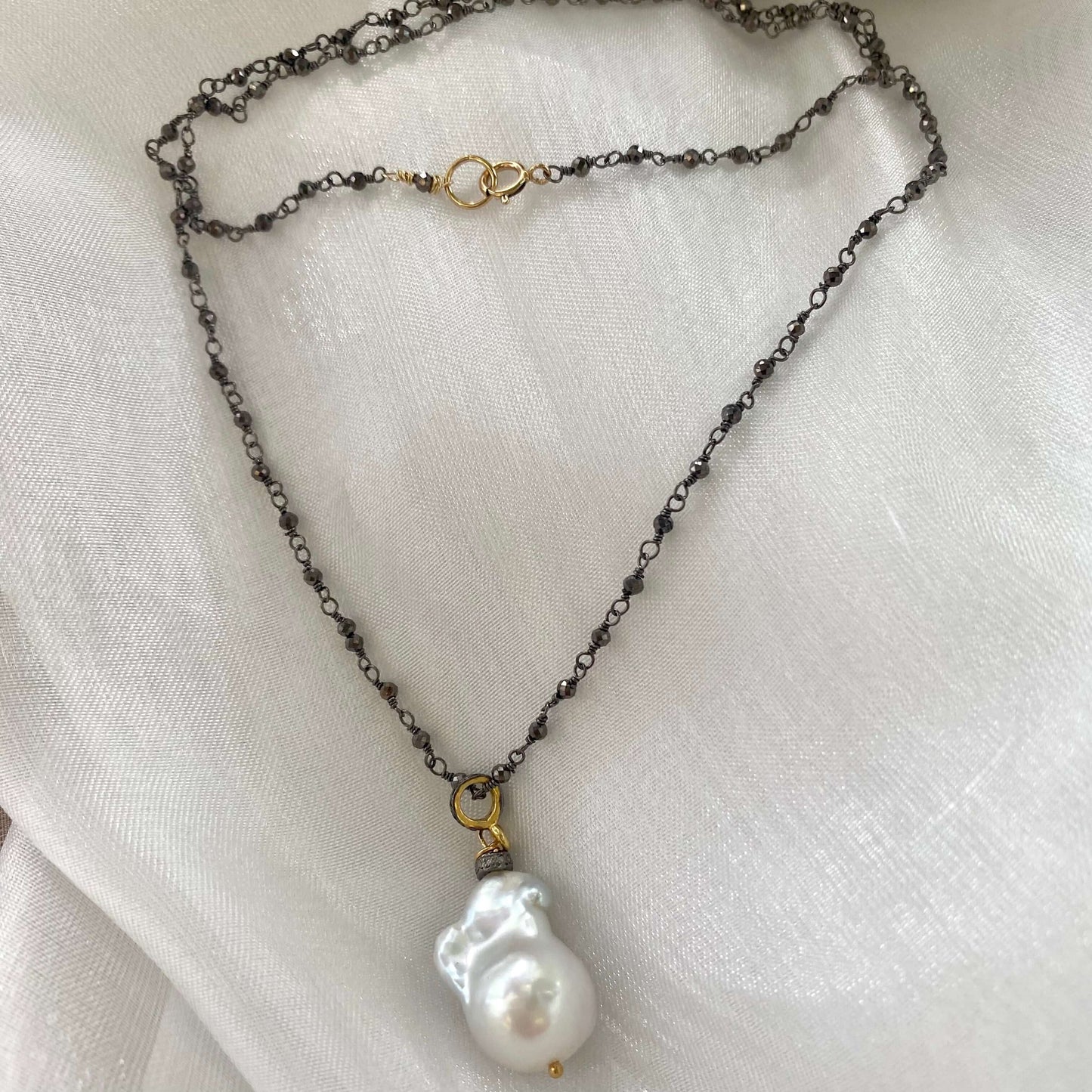 Pyrite rosary chain necklace displayed on white cloth table showing gemstones and gold details