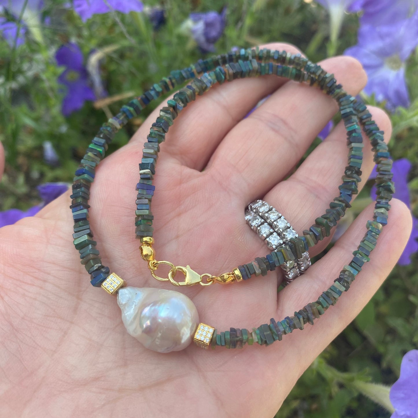 Black opal pearl necklace held in hand showing Ethiopian opal beads