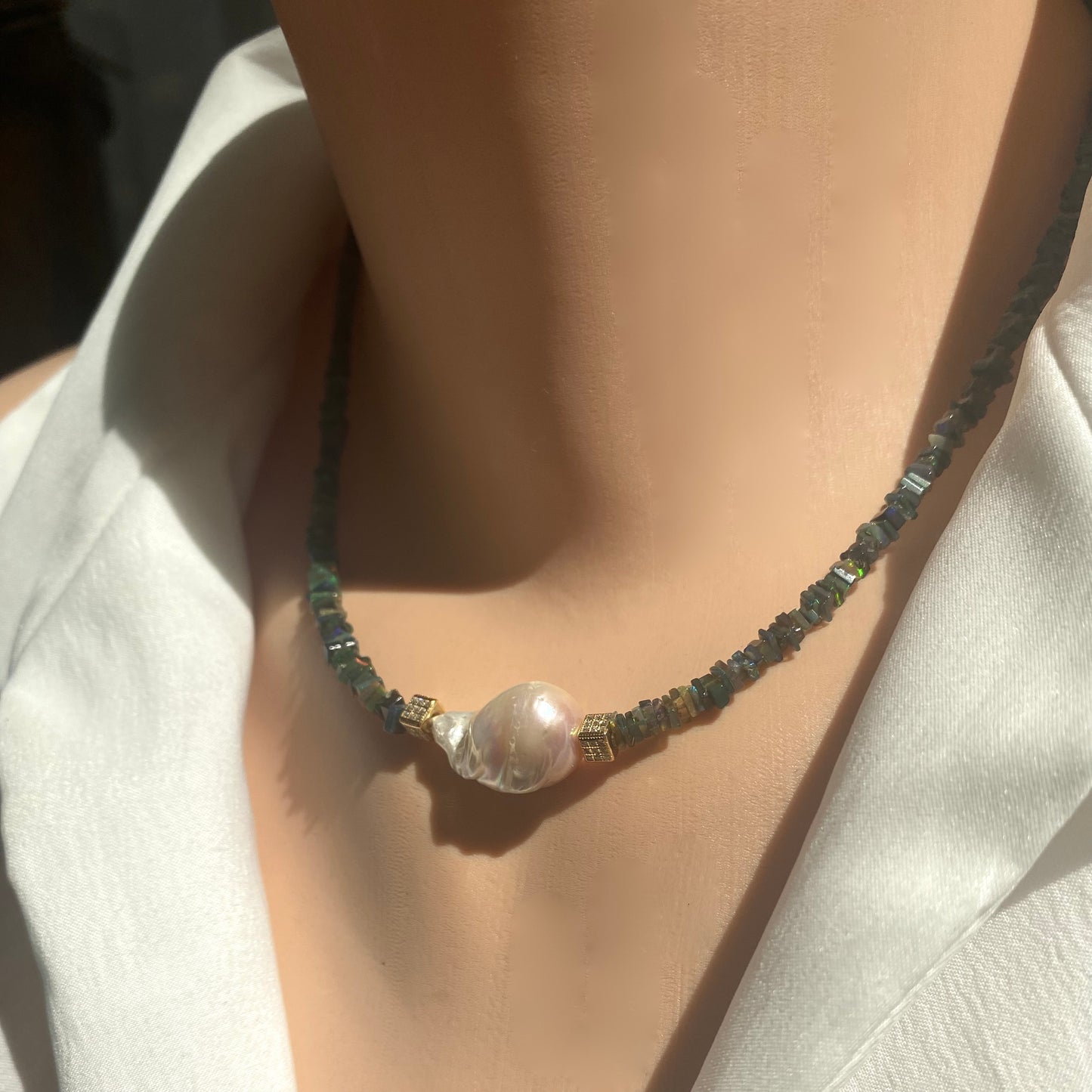 Black opal pearl necklace worn on mannequin, front view