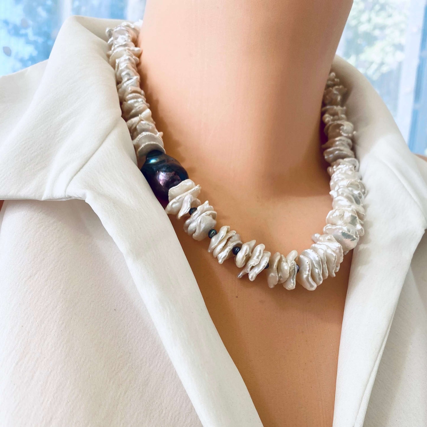 White cornflake pearl necklace with black baroque pearl pendant on a mannequin.