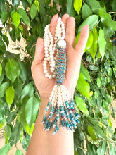 Load image into Gallery viewer, Bohemian Pearl Tassel Necklace held in hand, showcasing pearls, turquoise beads, and colorful tassels.
