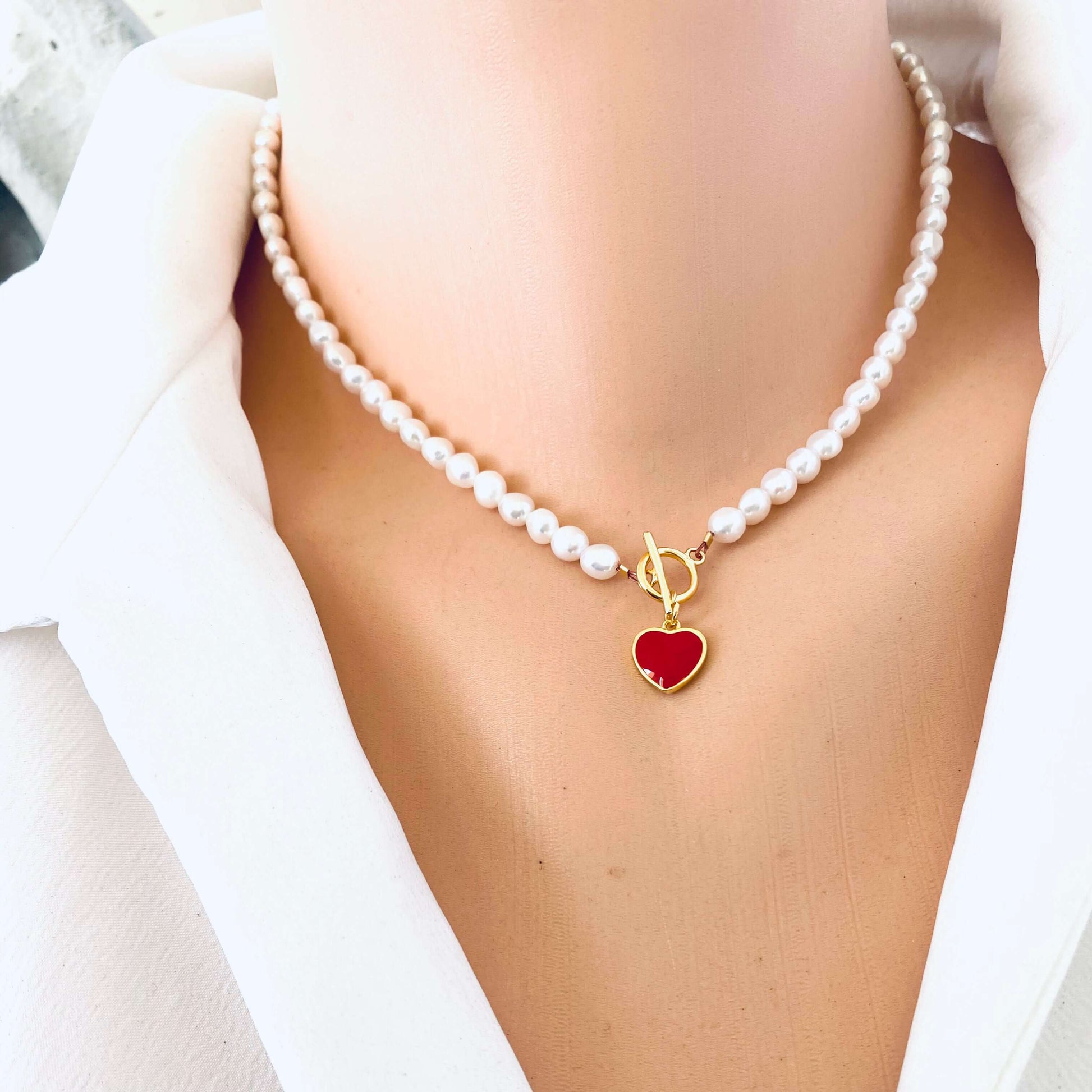 White Pearl Necklace with red heart charm displayed in frontal close-up on mannequin.