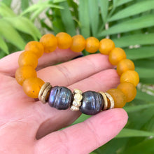 Load image into Gallery viewer, Black pearl bracelet featuring tangerine African recycled glass beads, showcasing vibrant colors and ethical craftsmanship.
