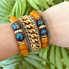 Load image into Gallery viewer, A collection of colorful bracelets, including a black pearl bracelet, showcasing vibrant tangerine and blue tones.
