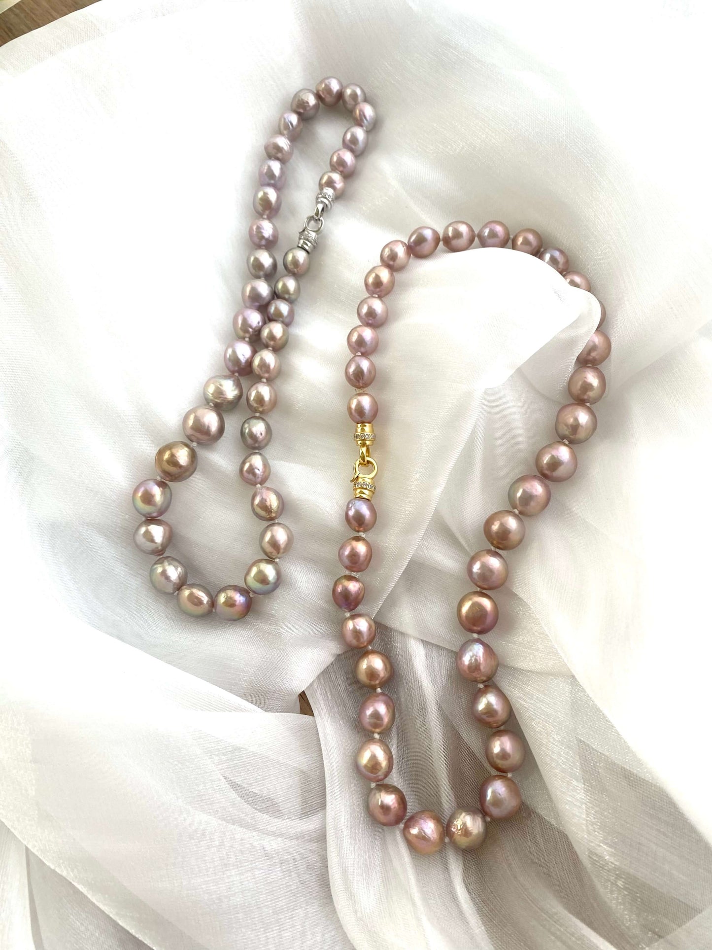 Pair of pink lavender pearl necklaces on white fabric, comparing soft iridescence and handmade Edison baroque design.