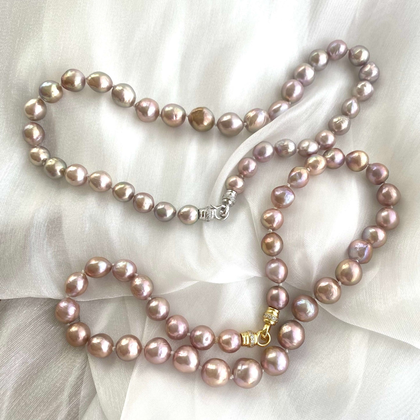 Two pink lavender pearl necklaces with slightly different lusters displayed on white cloth, showing natural variation.