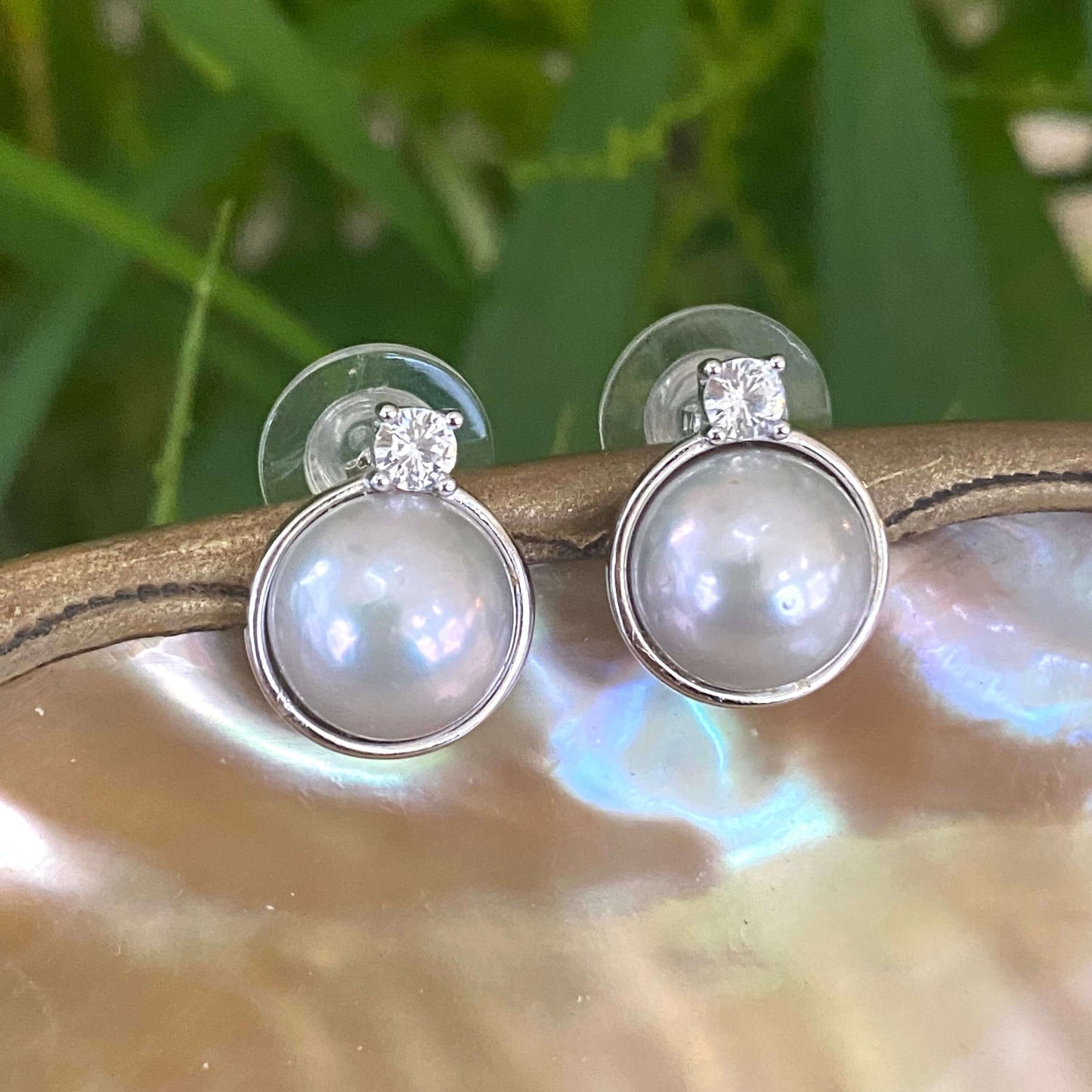 Silver grey pearl stud earrings with CZ set in gold vermeil against a natural background.