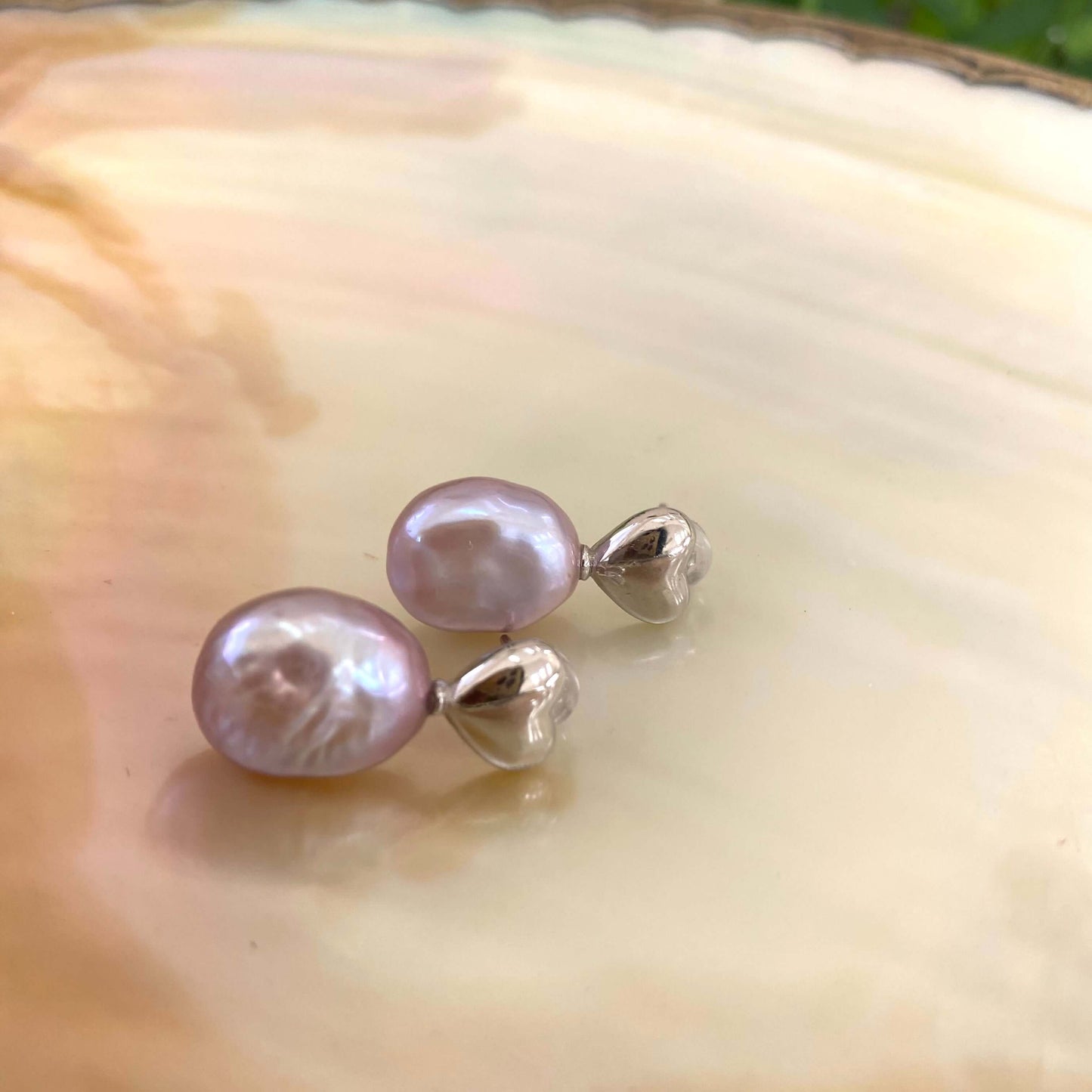 Heart Pearl Earrings – silver close-up against white pearl shell backdrop