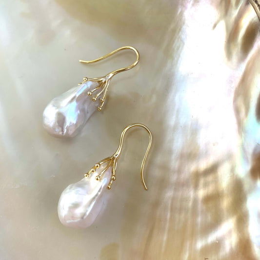 Side angle of white baroque pearl drop earrings showing organic shape and iridescence – handmade in Canada