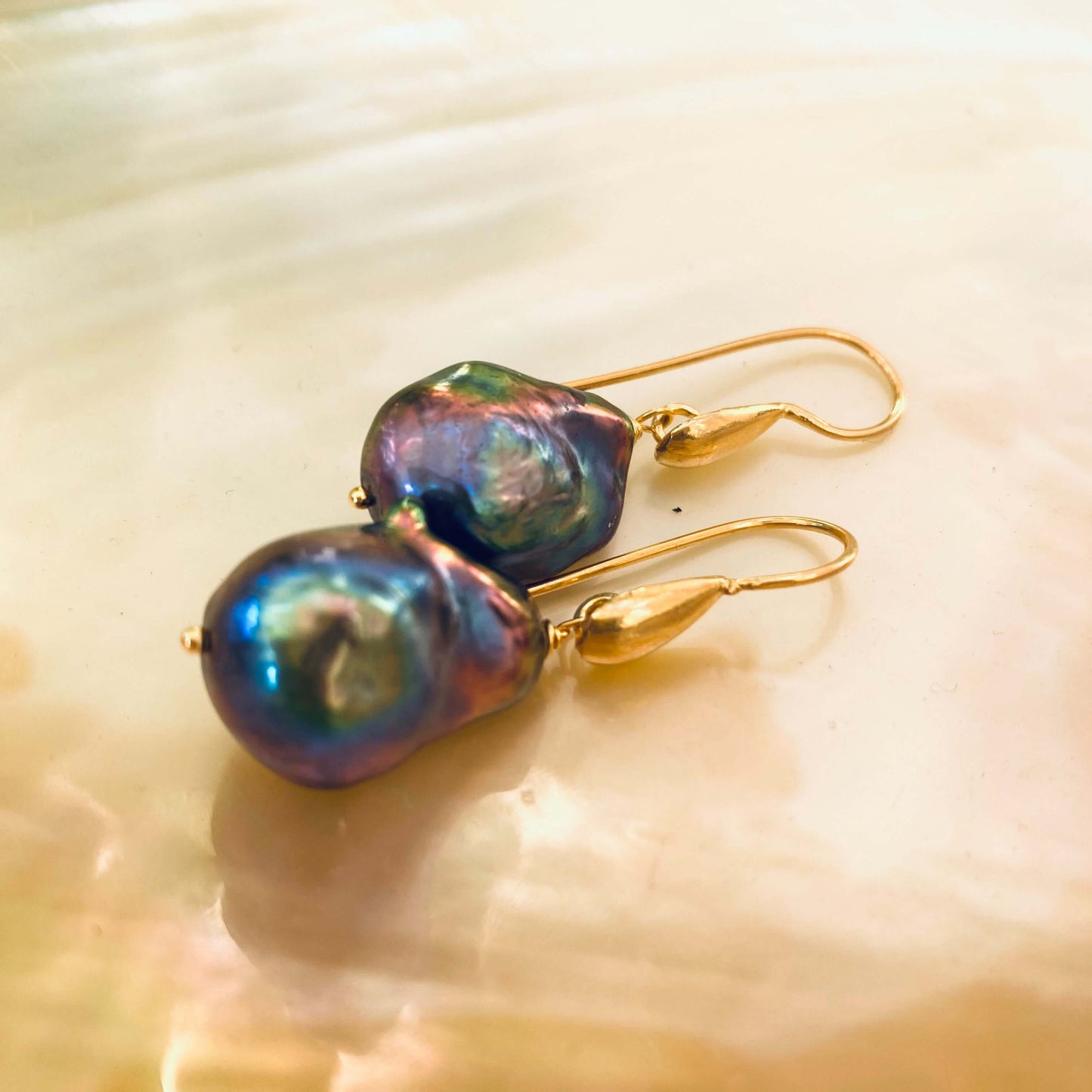 Handmade black baroque pearl drop earrings with gold vermeil hooks displayed on white pearl backdrop