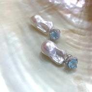Blue topaz pearl drop earrings displayed on white pearl shell background