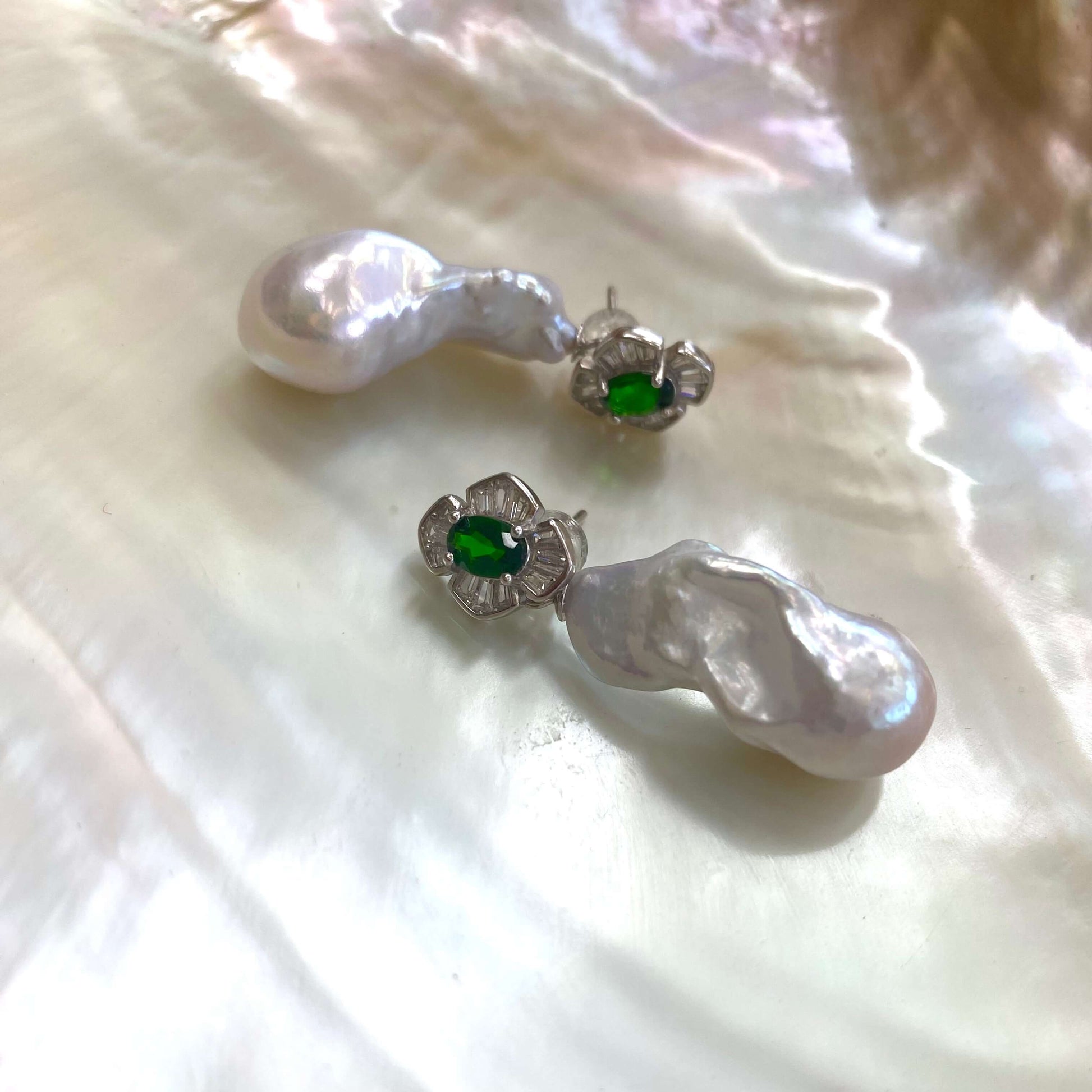 Close-up of green diopside baroque pearl drop earrings on white pearl shell background — elegant gemstone jewelry by Loulia Pearl Jewelry